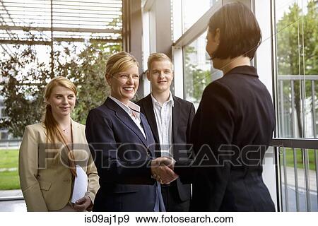 Stock Photo - Business team greeting young female colleague. Fotosearch