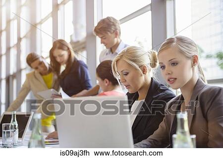 Stock Image - Businessman and businesswomen discussing documents at brainstorming meeting. Fotosearch