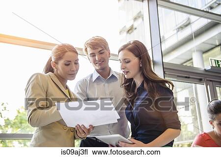 Businessman and businesswomen discussing documents at brainstorming meeting View Large Photo Image Stock Image - Businessman and businesswomen discussing documents at brainstorming meeting. Fotosearch