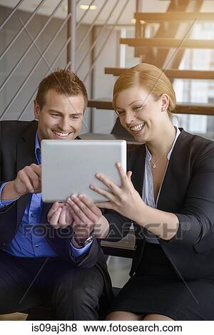Businessman and woman using digital tablet on office stairway View Large Photo Image Stock Photo - Businessman and woman using digital tablet on office stairway. Fotosearch