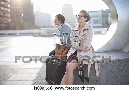 Stock Photograph - Businessman and woman waiting on city rooftop parking lot. Fotosearch