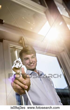 Stock Photograph - Businessman holding electric plug. Fotosearch