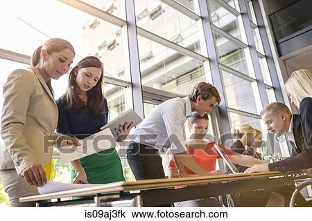 Stock Image - Businessmen and businesswomen at brainstorming meeting. Fotosearch