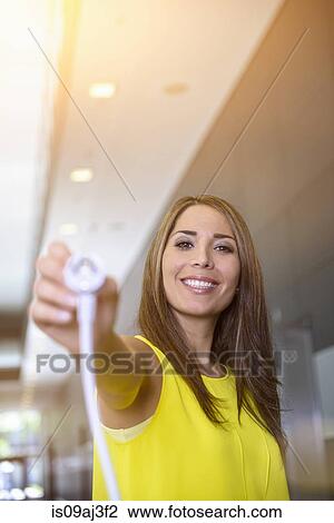 Stock Image - Businesswoman holding electric plug. Fotosearch