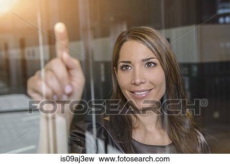 Businesswoman pointing out of glass window View Large Photo Image Stock Photo - Businesswoman pointing out of glass window. Fotosearch