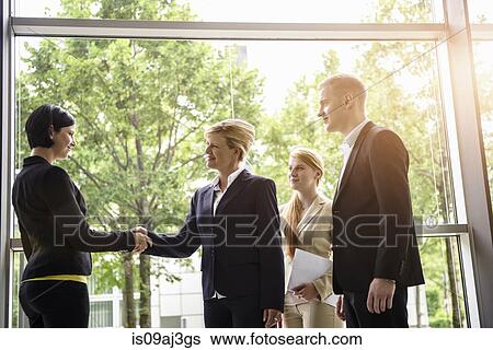 Businesswomen and men greeting client in office View Large Photo Image Stock Photograph - Businesswomen and men greeting client in office. Fotosearch