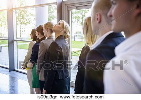 Picture - Businesswomen and men waiting in a row in office. Fotosearch