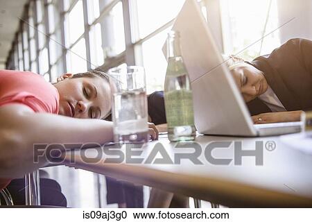 Stock Image - Businesswomen exhausted at brainstorm meeting. Fotosearch