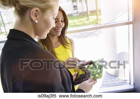 Stock Photography - Businesswomen using digital tablet for discussion. Fotosearch