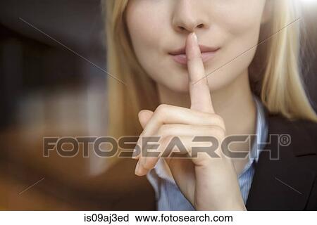 Stock Image - Close up cropped image of young businesswoman with finger on lips. Fotosearch