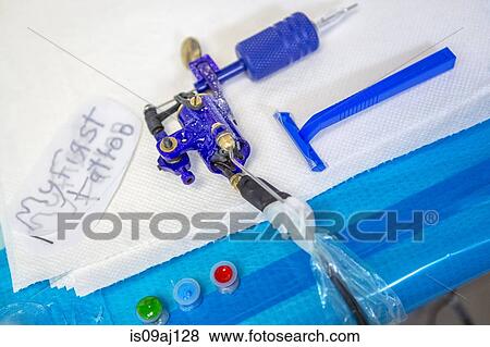 Stock Photo - Close up of tattoo gun, razor, ink and "my first tattoo" design on trace paper. Fotosearch