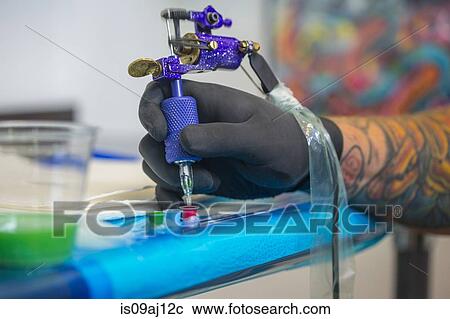 Close up of tattooist hand dipping tattoo gun's needle into red ink View Large Photo Image Stock Image - Close up of tattooist hand dipping tattoo gun's needle into red ink. Fotosearch