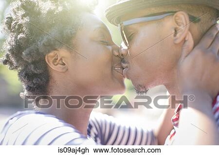 Close up of young couple kissing in park View Large Photo Image Stock Image - Close up of young couple kissing in park. Fotosearch
