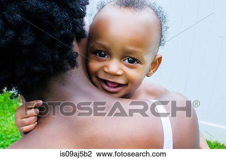Close up portrait of baby boy looking over mother's shoulder View Large Photo Image Stock Image - Close up portrait of baby boy looking over mother's shoulder. Fotosearch