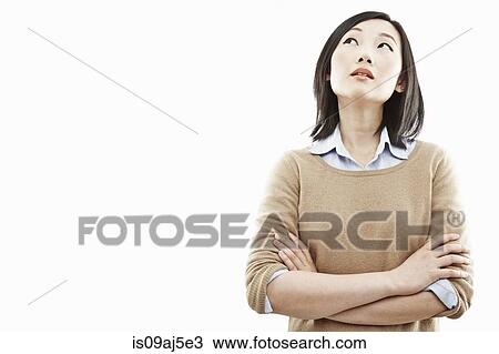 Stock Image - Close up studio portrait of young woman with arms folded. Fotosearch