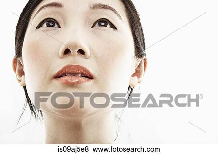 Stock Photo - Close up studio portrait of young woman looking up. Fotosearch