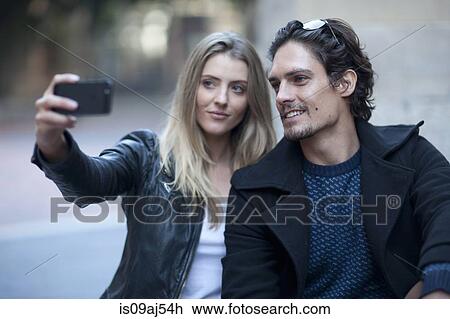 Couple taking self portrait with smartphone on city street View Large Photo Image Stock Image - Couple taking self portrait with smartphone on city street. Fotosearch