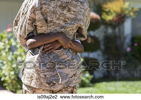 Stock Image - Cropped rear view of female soldier hugging son on homecoming. Fotosearch