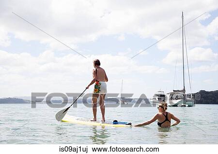 Daughter pushing senior mothers paddleboard at sea View Large Photo Image Stock Image - Daughter pushing senior mothers paddleboard at sea. Fotosearch
