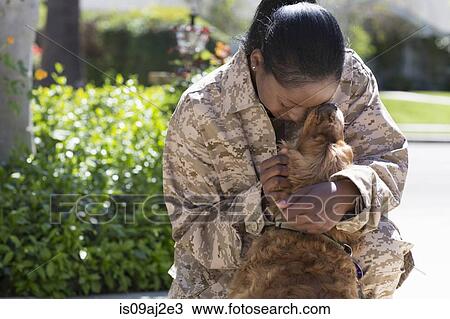 Stock Image - Female soldier hugging pet dog on street at homecoming. Fotosearch