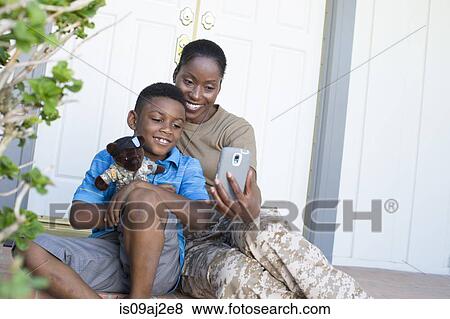 Stock Photo - Female soldier taking selfie with son at front door on homecoming. Fotosearch