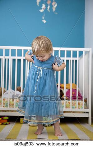 Stock Image - Female toddler admiring her party dress in bedroom. Fotosearch