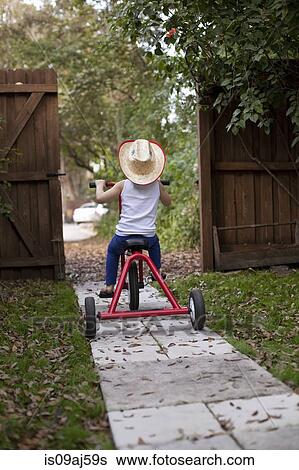 Four year old girl riding her tricycle out of garden gate View Large Photo Image Stock Photograph - Four year old girl riding her tricycle out of garden gate. Fotosearch