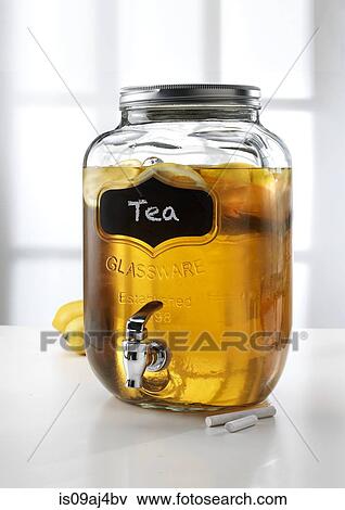 Stock Photo - Glass jar with tap dispenser containing fresh lemon tea drink. Fotosearch