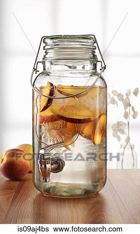 Glass jar with tap dispenser containing fresh peach drink View Large Photo Image Stock Photograph - Glass jar with tap dispenser containing fresh peach drink. Fotosearch