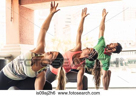 Stock Photograph - Group of young adults doing yoga. Fotosearch