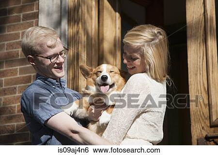 Happy young couple with corgi dog in arms outside front door View Large Photo Image Stock Photograph - Happy young couple with corgi dog in arms outside front door. Fotosearch