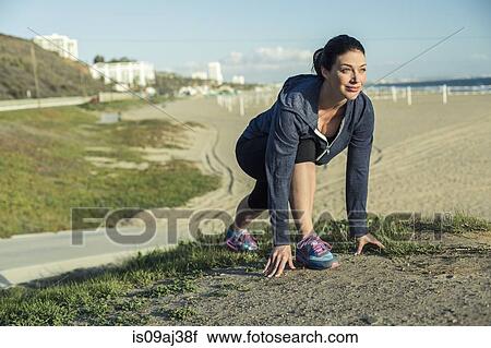 Stock Image - Jogger on her mark by beach. Fotosearch