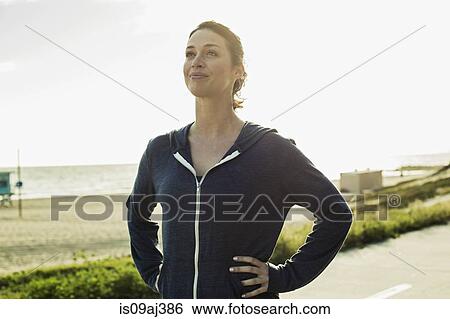 Stock Photograph - Jogger taking break on road by beach. Fotosearch