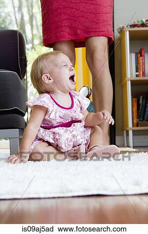 Stock Image - Legs of mid adult mother next to screaming baby daughter. Fotosearch