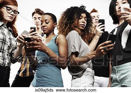 Stock Photograph - Low angle studio shot of six young adults texting on smartphone. Fotosearch