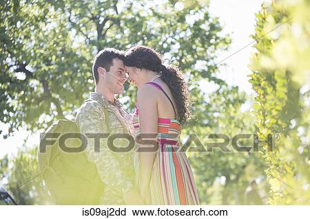 Stock Image - Male soldier holding hands with wife on street at homecoming. Fotosearch