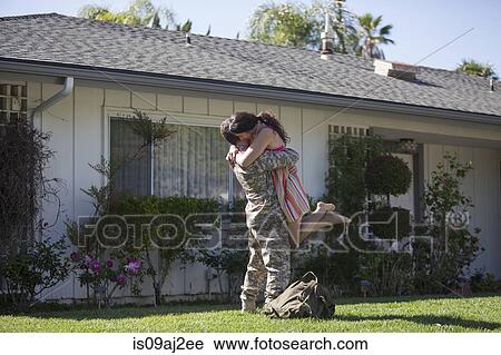 Stock Image - Male soldier hugging and lifting wife in garden on homecoming. Fotosearch