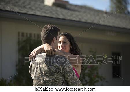 Stock Image - Male soldier hugging wife in garden on homecoming. Fotosearch