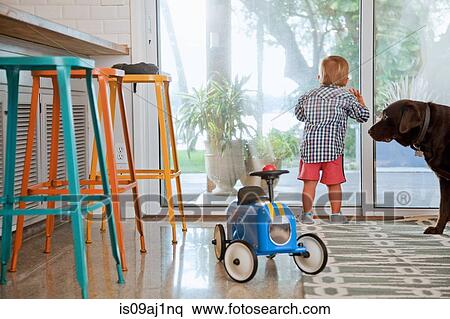 Stock Photography - Male toddler looking out of patio door in kitchen. Fotosearch
