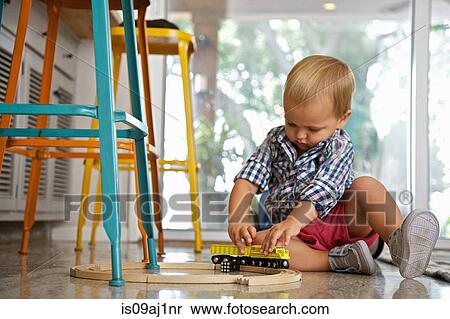 Male toddler playing with train set on kitchen floor View Large Photo Image Stock Photography - Male toddler playing with train set on kitchen floor. Fotosearch