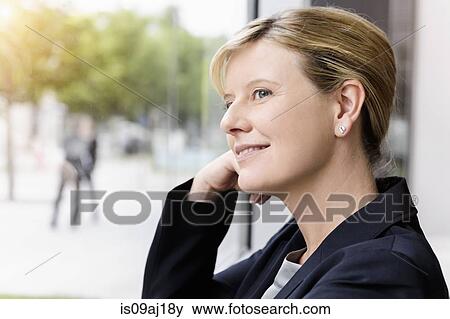Mature businesswoman gazing out of office window View Large Photo Image Stock Photo - Mature businesswoman gazing out of office window. Fotosearch
