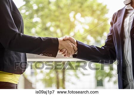 Mature businesswoman shaking hands with young female client View Large Photo Image Stock Photo - Mature businesswoman shaking hands with young female client. Fotosearch