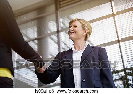 Stock Photograph - Mature businesswoman shaking hands with client. Fotosearch