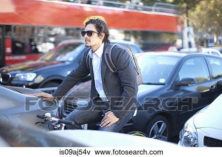 Stock Photo - Mid adult businessman cycling during rush hour. Fotosearch