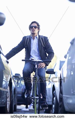 Mid adult businessman cycling in traffic congestion View Large Photo Image Stock Photo - Mid adult businessman cycling in traffic congestion. Fotosearch