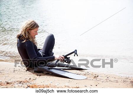 Mid adult female scuba diver preparing to dive on beach View Large Photo Image Stock Image - Mid adult female scuba diver preparing to dive on beach. Fotosearch