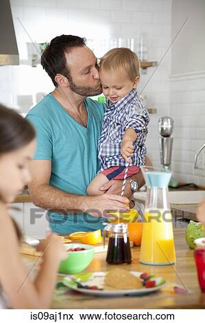 Mid adult man multi tasking breakfast with son and daughter View Large Photo Image Stock Photo - Mid adult man multi tasking breakfast with son and daughter. Fotosearch