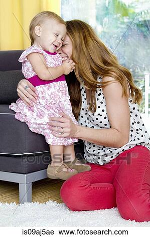 Mid adult mother and baby daughter sharing a tender cuddle View Large Photo Image Stock Image - Mid adult mother and baby daughter sharing a tender cuddle. Fotosearch