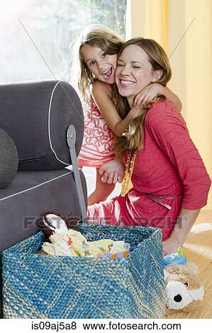 Stock Photo - Mid adult mother being hugged by daughter. Fotosearch