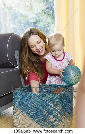 Stock Image - Mid adult mother squeezing soft toy for baby daughter. Fotosearch